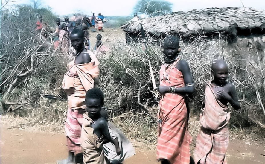 Ein Besuch in einem Massai-Dorf  in Kenia 1980:Die Hütten (Boma) der Massai sind aus getrocknetem Kuhdung, Lehm und einzelnen Holzpfosten hergestellt. In den Hütten, in denen auch Kleintiere schlafen, brennt ständig ein kleines Feuer, das am Tag zum Kocheá