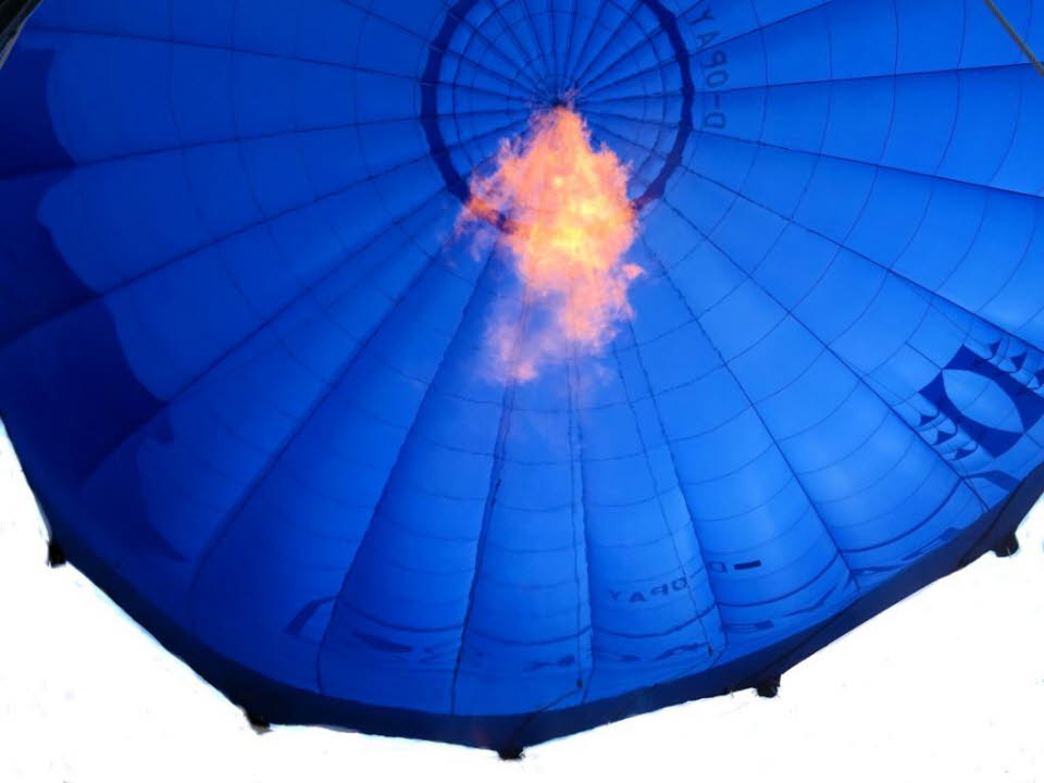 1Eine Himmelsreise in einer Kathedrale aus Stoff und Licht mit der KI betrachtet. Das Bild zeigt den Innenraum eines Heißluftballons, so wie man ihn sieht, wenn man direkt von unten in die Ballonhülle blickt. Was genau ist zu sehen? Die Ballonhülle wölbt 