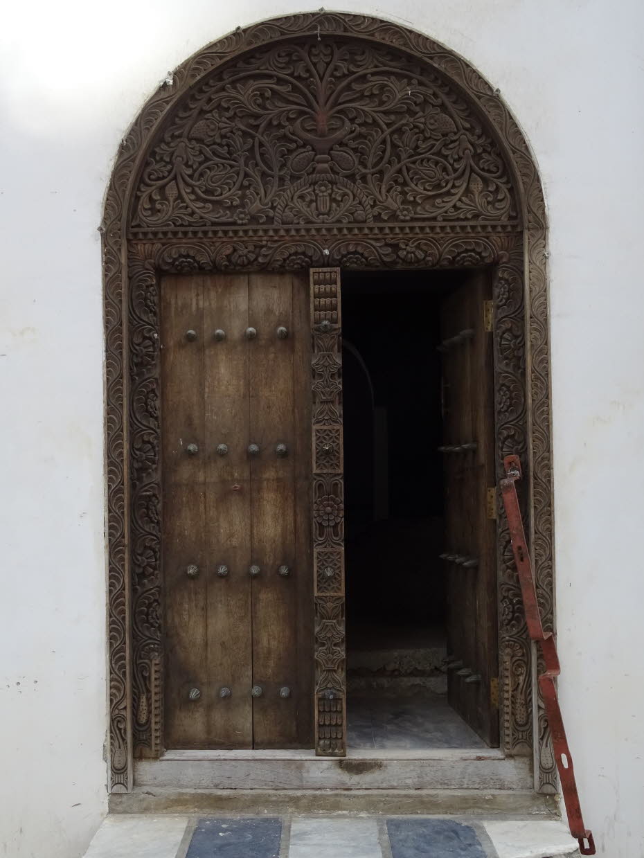 Indische Tür Zanzibar Stonetown: Stone Town bzw. Zanzibar Stadt ist bekannt dür kunstvoll geschnitzte Türen. Der waagerechte Sturz deutet auf arabische Bewohner hin. Die Inder haben Bögen.