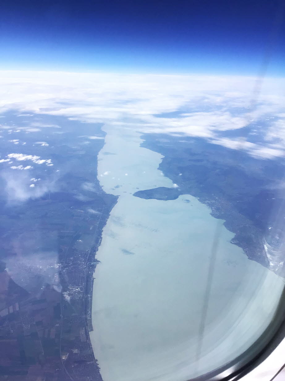 Balaton: Das Foto zeigt den Balaton (Plattensee) in Ungarn aus der Luftperspektive.Geografie: Mit einer Länge von ca. 79 km ist er der größte Binnensee Mitteleuropas. Lage: Der See befindet sich in Westungarn. Charakteristika: Er ist ein flacher Steppense