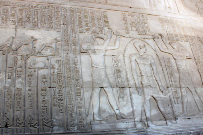 Das Relief auf der rechten Steinwand zeigt den falkenköpfigen Horus und den ibisköpfigen Thoth, die Neos Dionysos (Ptolemaios XII.) mit Weihewasser übergießen, links steht der krokodilköpfige Sobek